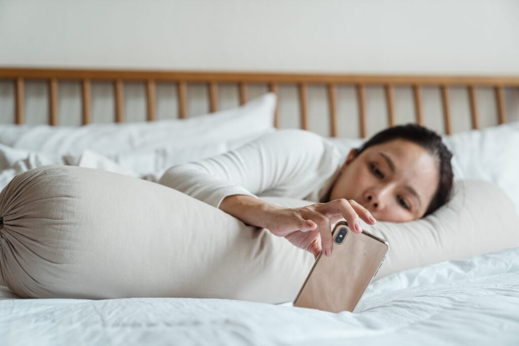 lazy mother in bed watching mobile phone
